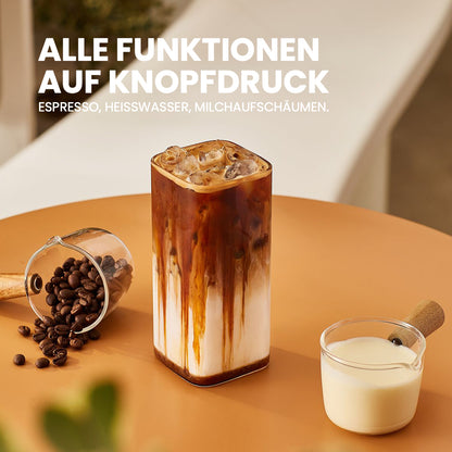 Ein Glas Eiskaffee auf einem Tisch, neben einer Schale mit Kaffeebohnen und einer kleinen Kanne Milch.